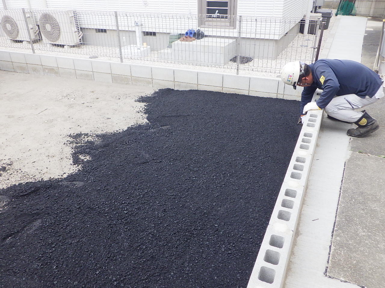 ブロックの際で舗装材を敷き均す作業